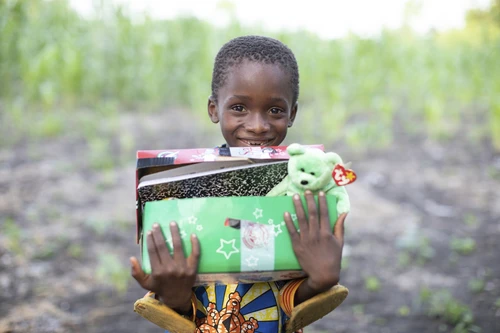 Child holding Operation Christmas Child box